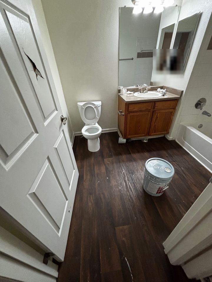 Bathroom before cleaning, with a bucket and items left out